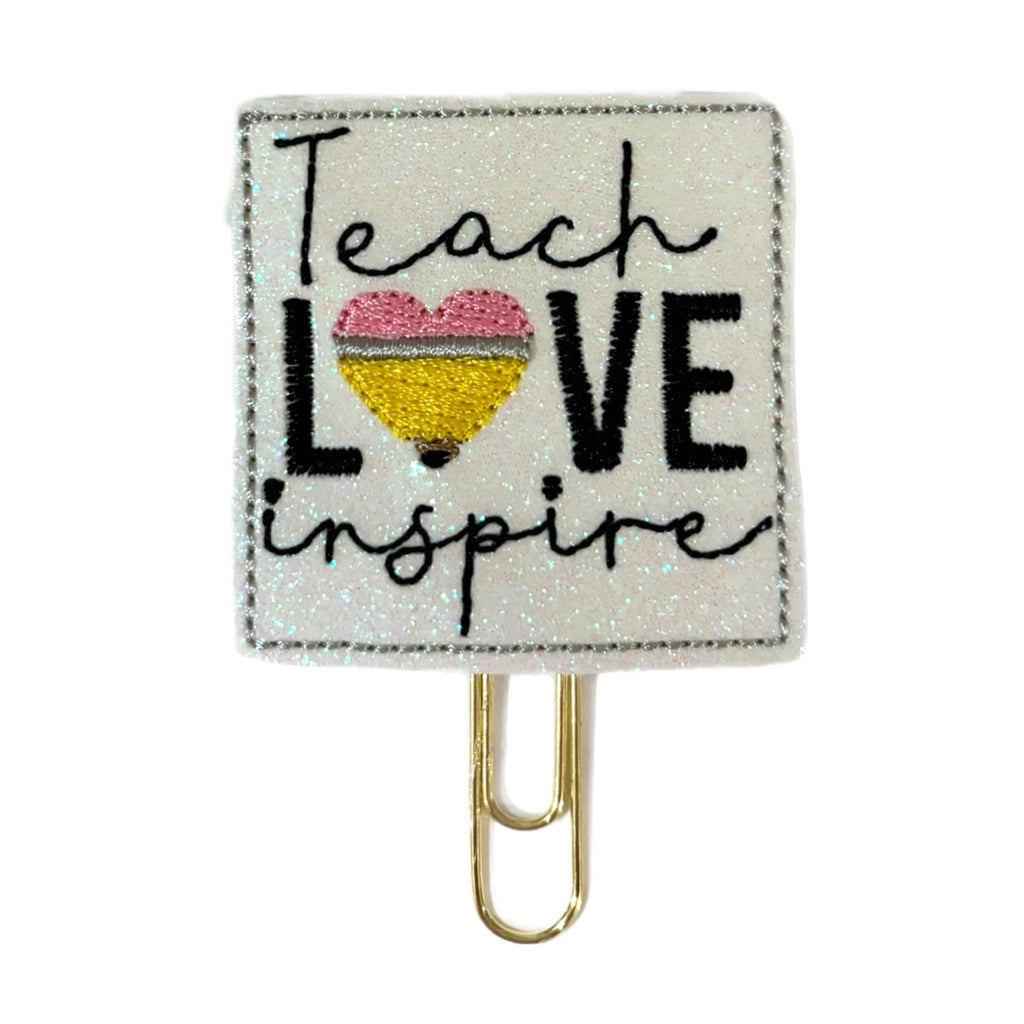 Teach, Love, Inspire novelty paper clip from Clip Chicks. The words along with a heart shaped pencil are embroidered on a shimmery piece of felt before being trimmed and attached to a paper clip. Makes a great techer's gift and bookmark or planner clip.