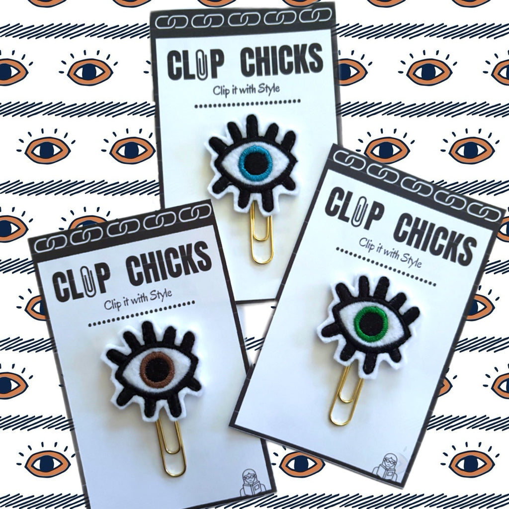 Clip Chicks' Evil Eye novelty paper clips  are shown in their packaging. there is a blue eye, a brown eye and a green eye in this picture.