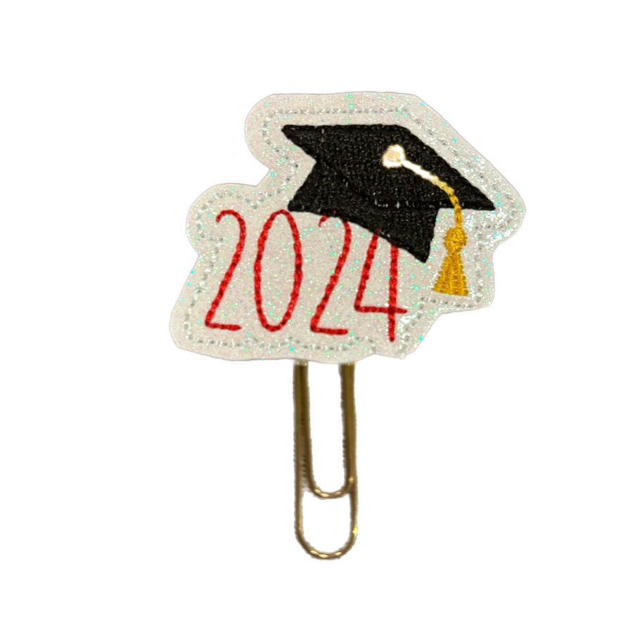 Graduate 2024 Clip Chicks novelty paper clip is a feltie embroidered to read '2024" with a graduation cap over the 24. The feltie is attached to a gold toned paper clip.