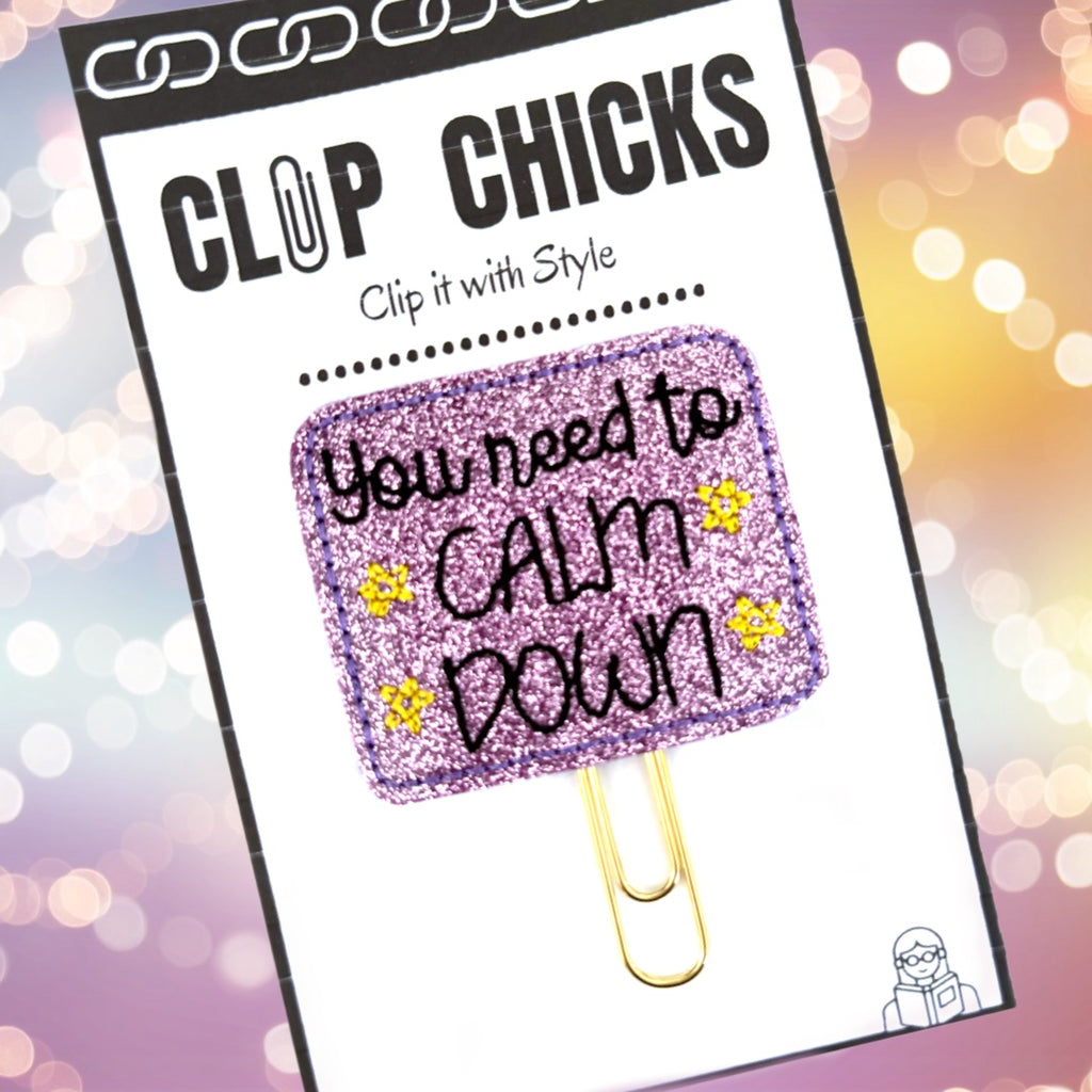 Clip Chicks' You Need to Calm Down novelty paper clip is shown in its package against a lavender and gold glowing background.