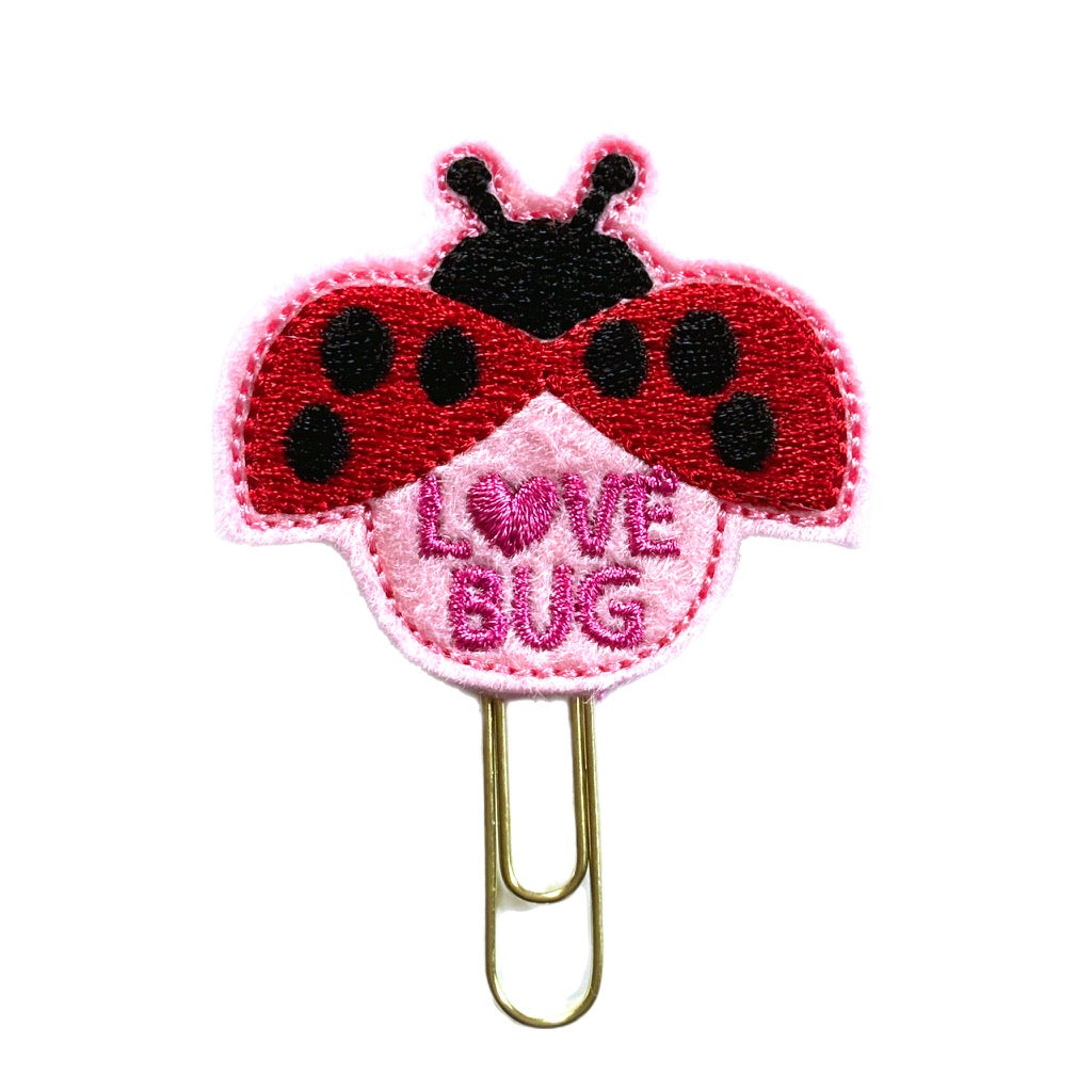 A cute novelty paper clip for Valentine's Day gifting. It's a feltie shaped like a ladybug in pink, red and black with the words, Love Bug written on it, then the feltie is attached to a gold toned paper clip, great for bookmarking pages and organizing papers.