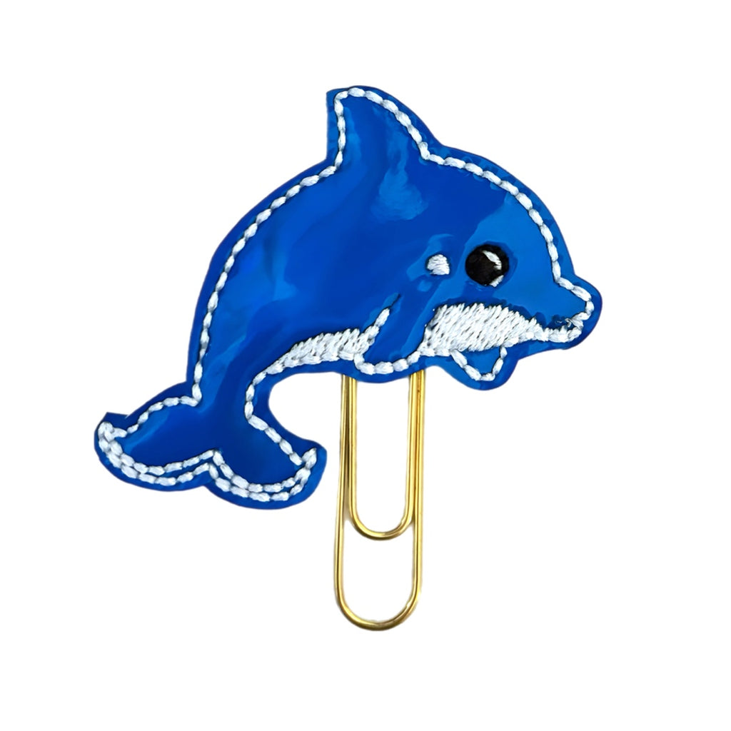 Blue vinyl dolphin with white embroidery and black eyes attached to a paper clip. This Clip Chicks novelty paper clip is perfect for summer reading and writing enhancements.