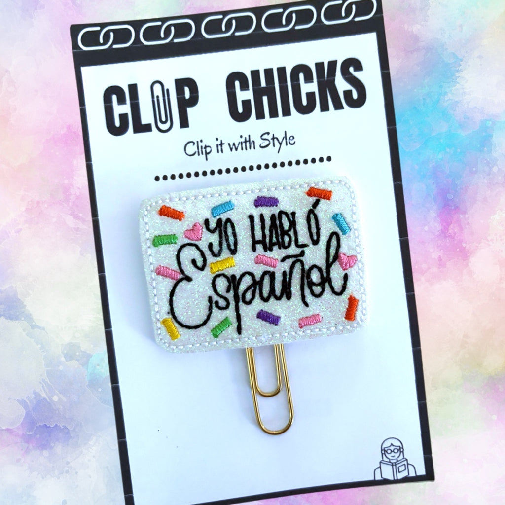 I Speak Spanish novelty paper clip from Clip Chicks is shown in its package against a pale pastel background.