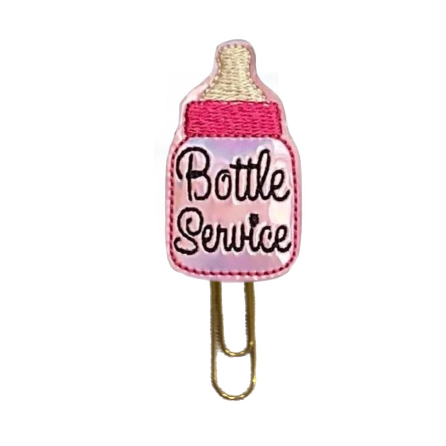 Bottle Service novelty paper clip from Clip Chicks is a cute bookmark or planner clip that is shaped like a pink bottle. The embroidered bottle is attached to a planner clip.