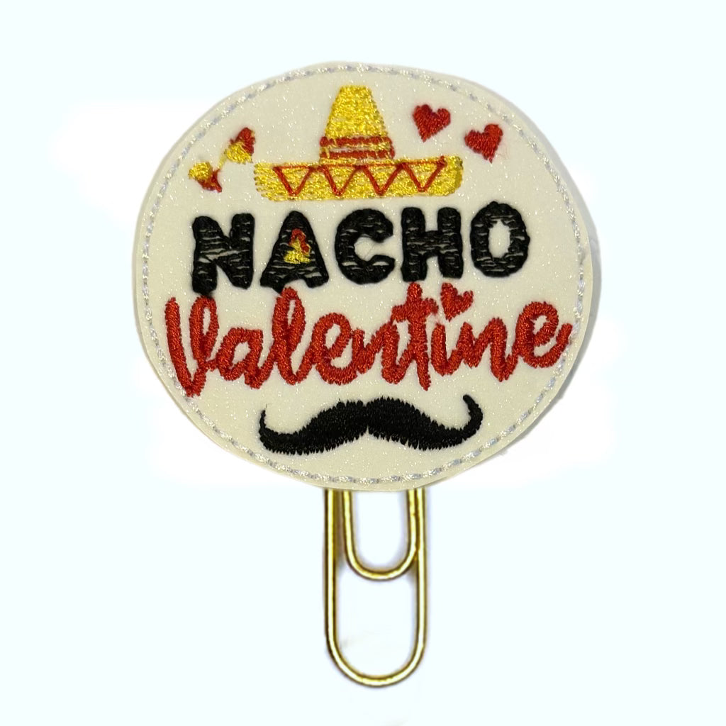 Nacho Valentine novelty paper clip. Gold toned paper clip is attached to a round feltie made from white glittery vinyl with Nacho Valentine and a mustache, sombrero and tiny hearts embroidered on it.