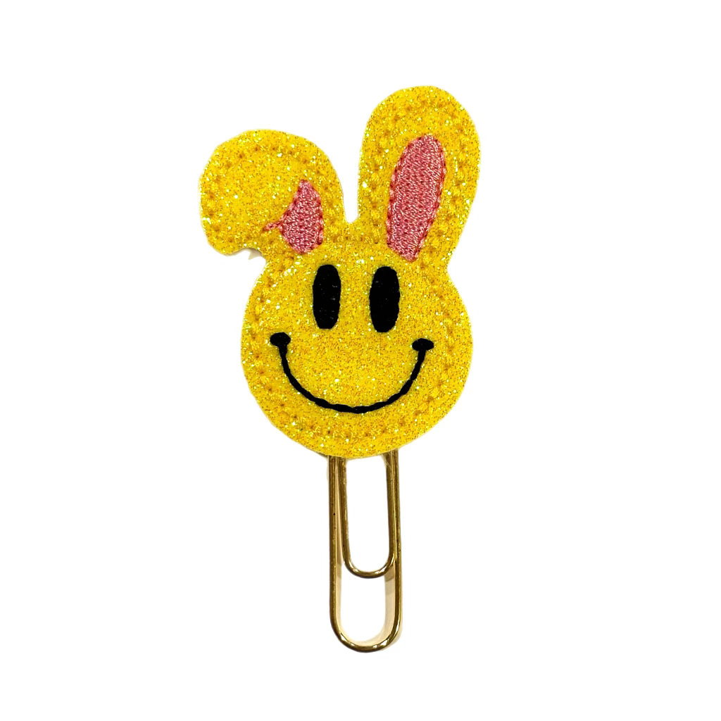 A Clip Chicks novelty paper clip shaped like a happy face with bunny ears,