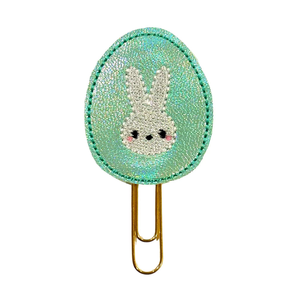 A Clip Chicks novelty paper clip shaped like an Easter egg with a bunny embroidered on it.