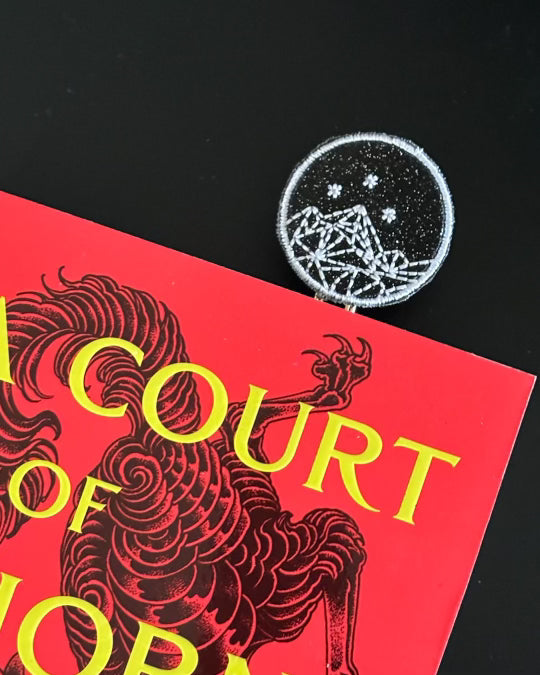 A picture of the Clip Chicks ACOTAR inspired bookmark sticking out from the book, A Court of Thorns and Roses.