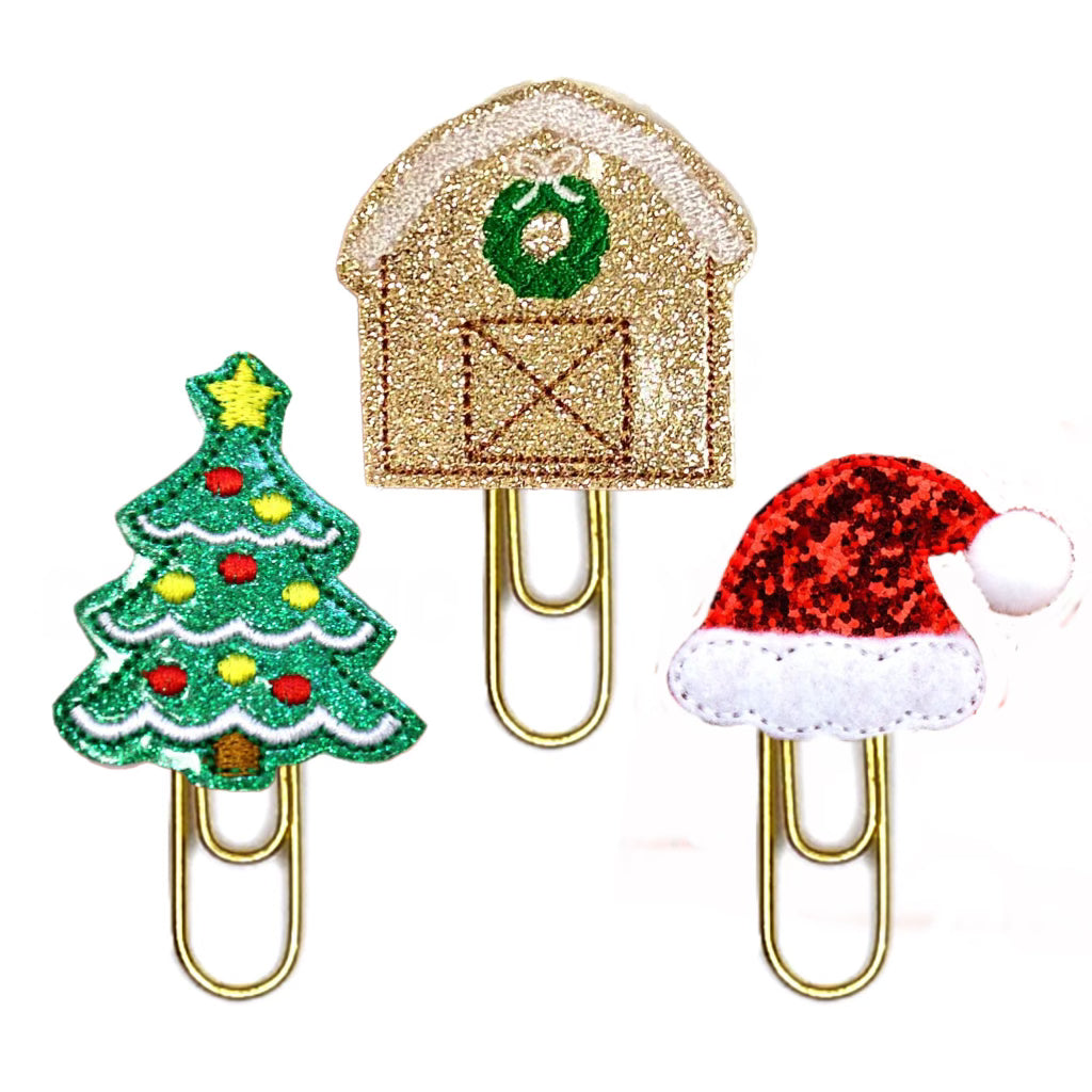 Glittery Christmas Trio of novelty paper clips include a Christmas tree, a Barn with a Wreath on it, and a red glittery Santa's Hat, all three are attached to gold toned paper clips.