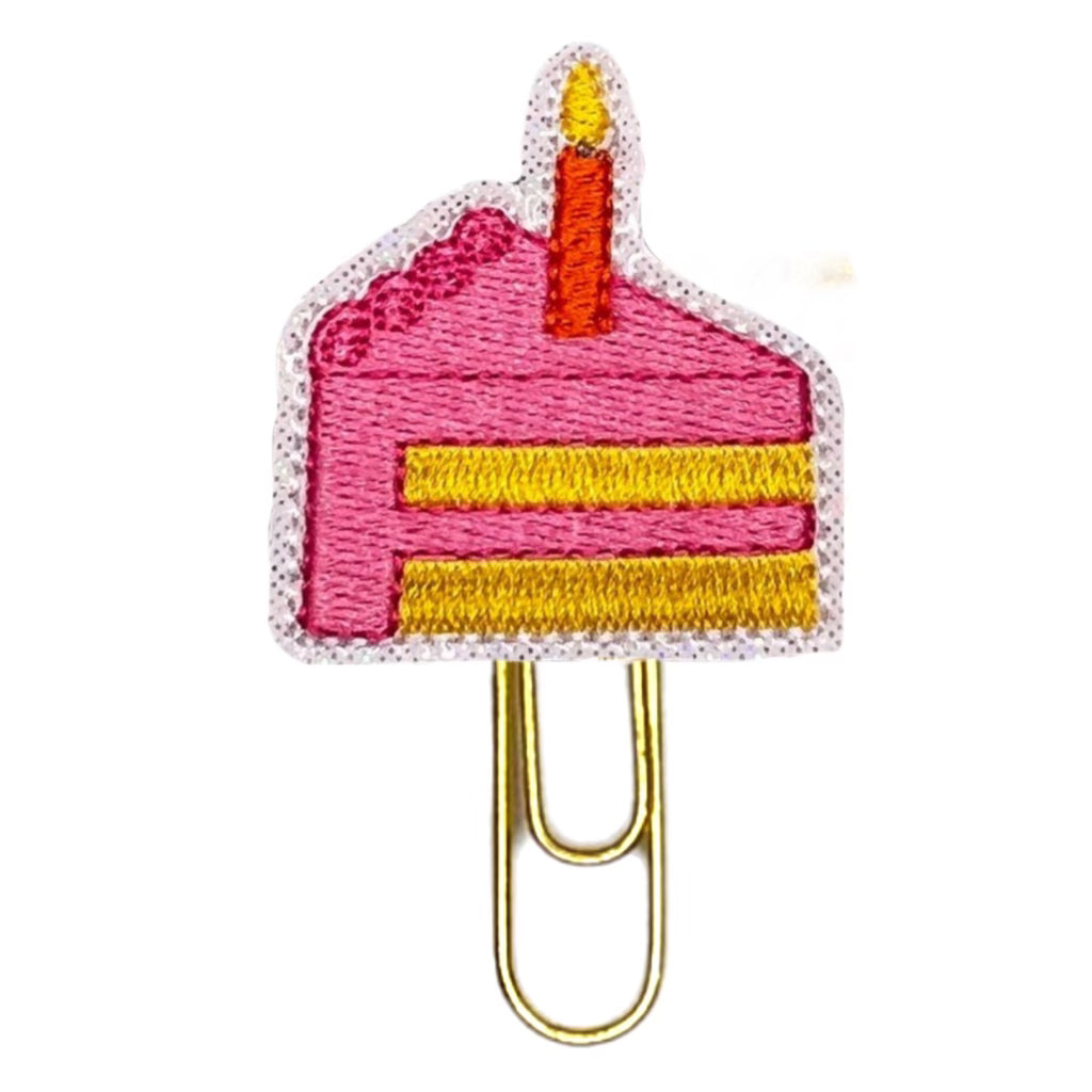 Slice of Birthday Cake with a Candle is embroidered onto felt and vinyl and attached to a paper clip.