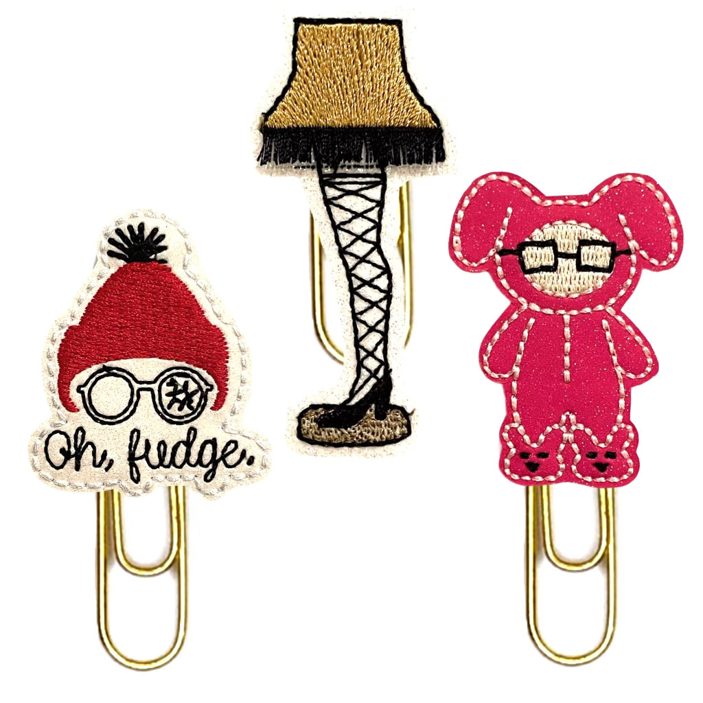 A Christmas Story-inspired set of novelty paper clips from Clip chicks, include a lamp leg clip, a boy ina bunny suit clip and an Oh, Fudge clip.