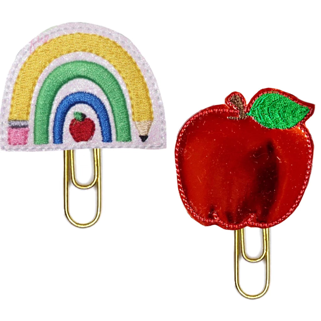 A set of Clip Chicks novelty paper clips  are shown. Set includes a rainbow shaped from pencils and apples and a red shiny apple, both are attached to paper clips.