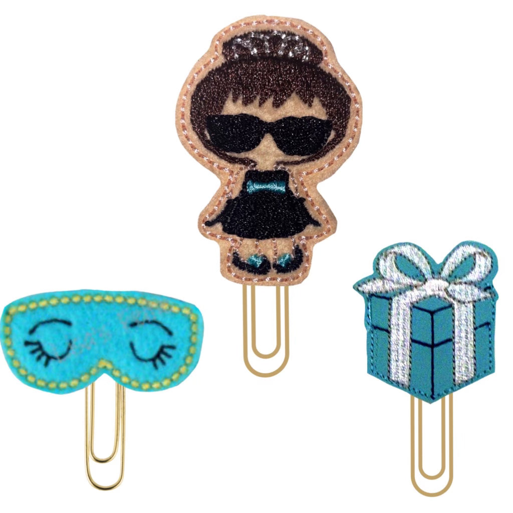 Trio of Breakfast at Tiffany's inspired novelty paper clips include a mini Audrey Hepburn, a blue sleeping mask, and a Tiffany blue box with a ribbon.