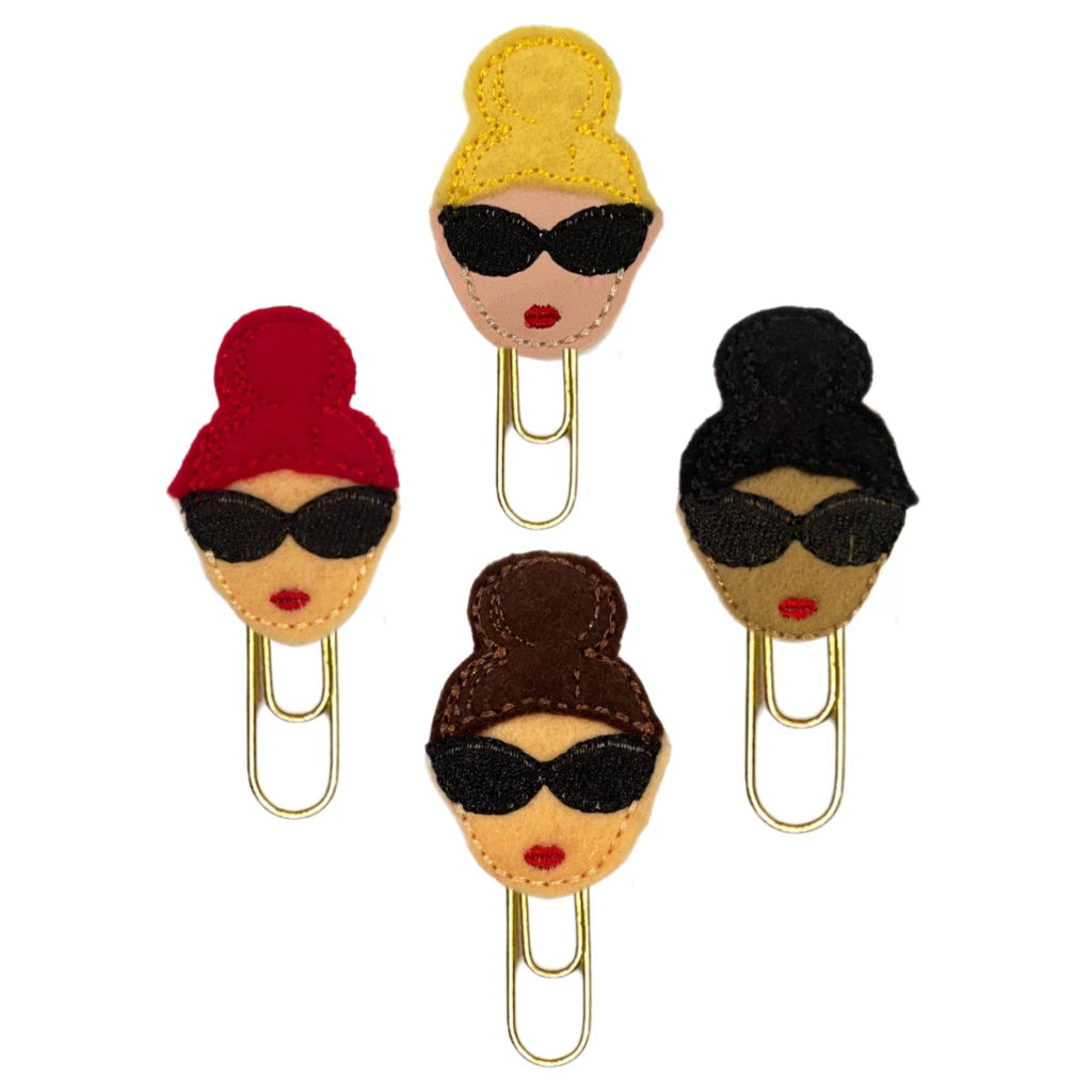 Bun Girl novelty paper clips are shown in the four color-ways available. A blonde, a red-fead, a burnette and black hair with dark complexion. They are shown against a white background.