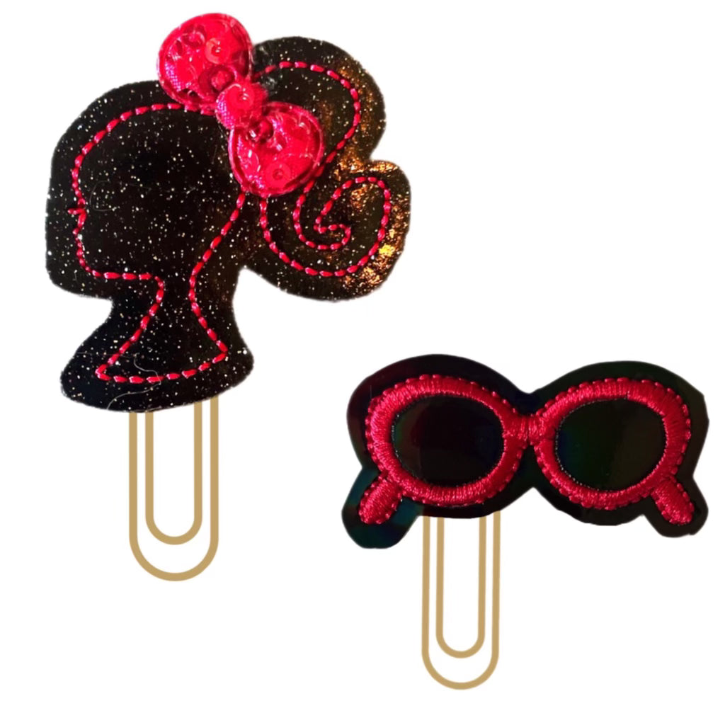 Doll and Shades set of Clip Chicks' novelty paper clip are shown, both are black glittery vinyl with hot pink embroidery felties that are attached to paper clips.