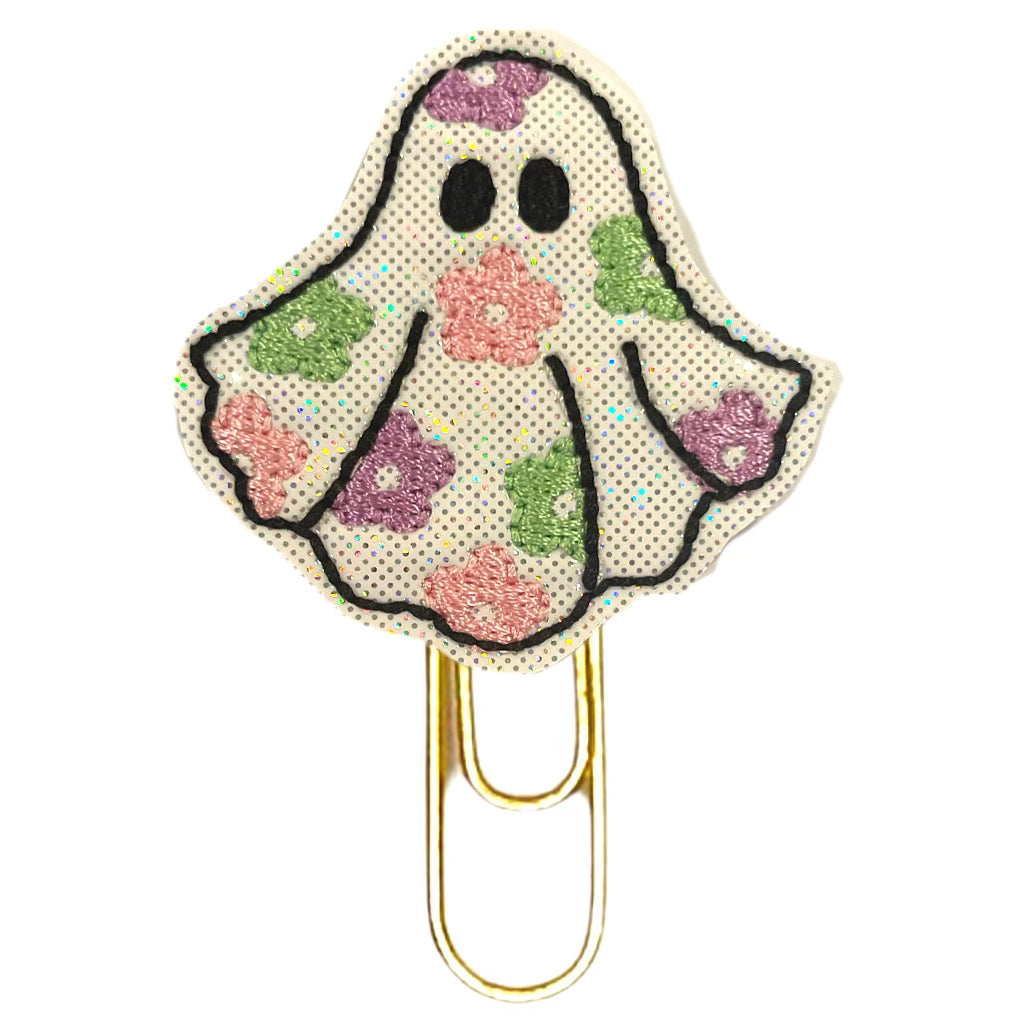 A flower ghost embroidered on vinyl and felt and attached to a gold tone paper clip.