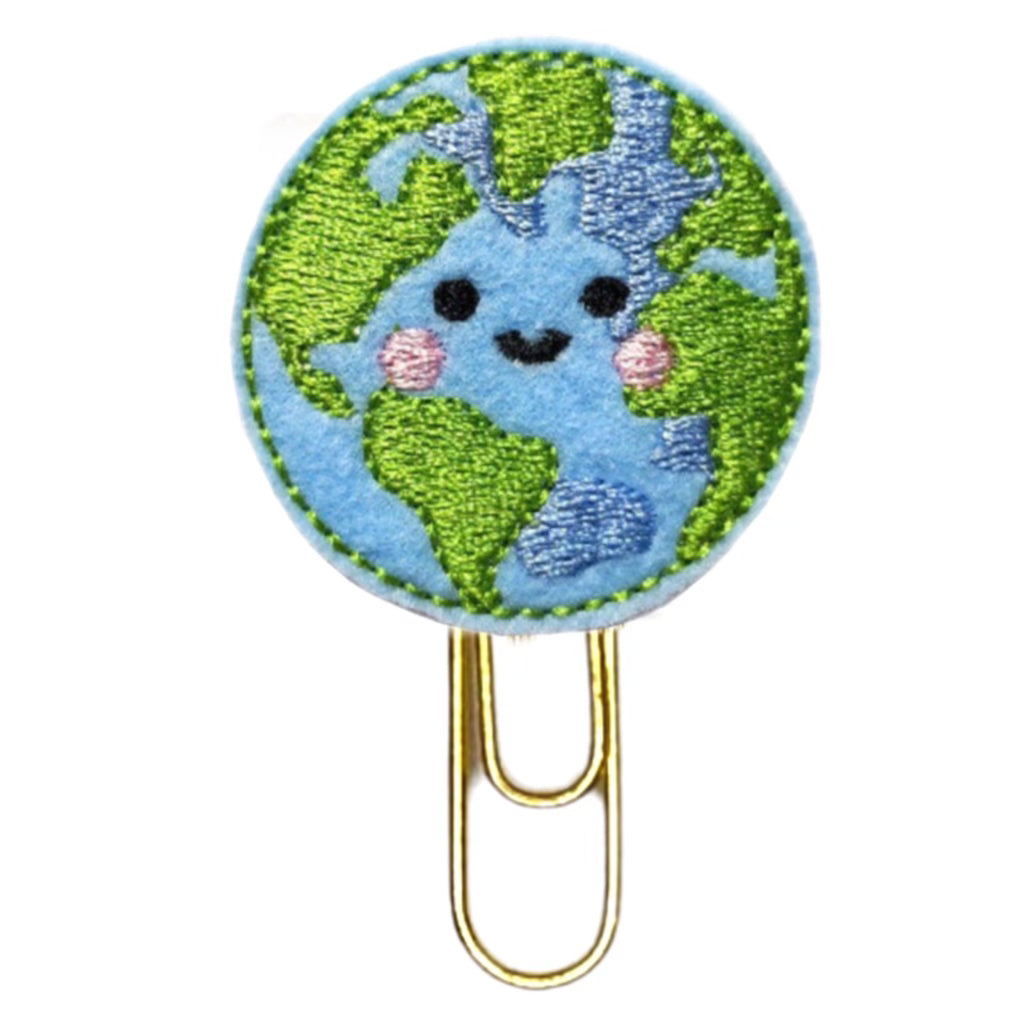 Happy Earth novelty paper clip from Clip Chicks is shaped like a globe with a happy face embroidered onto the felt circle and attached to a gold toned paper clip.