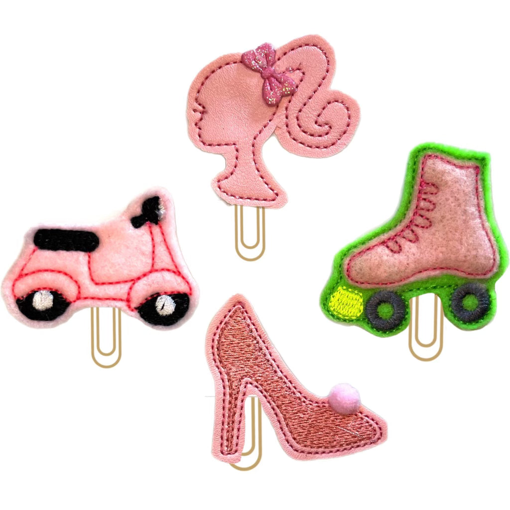 Barbie-themed set of four novelty paper clips in shades of pink, a doll head, vespa, roller skate and shoe.