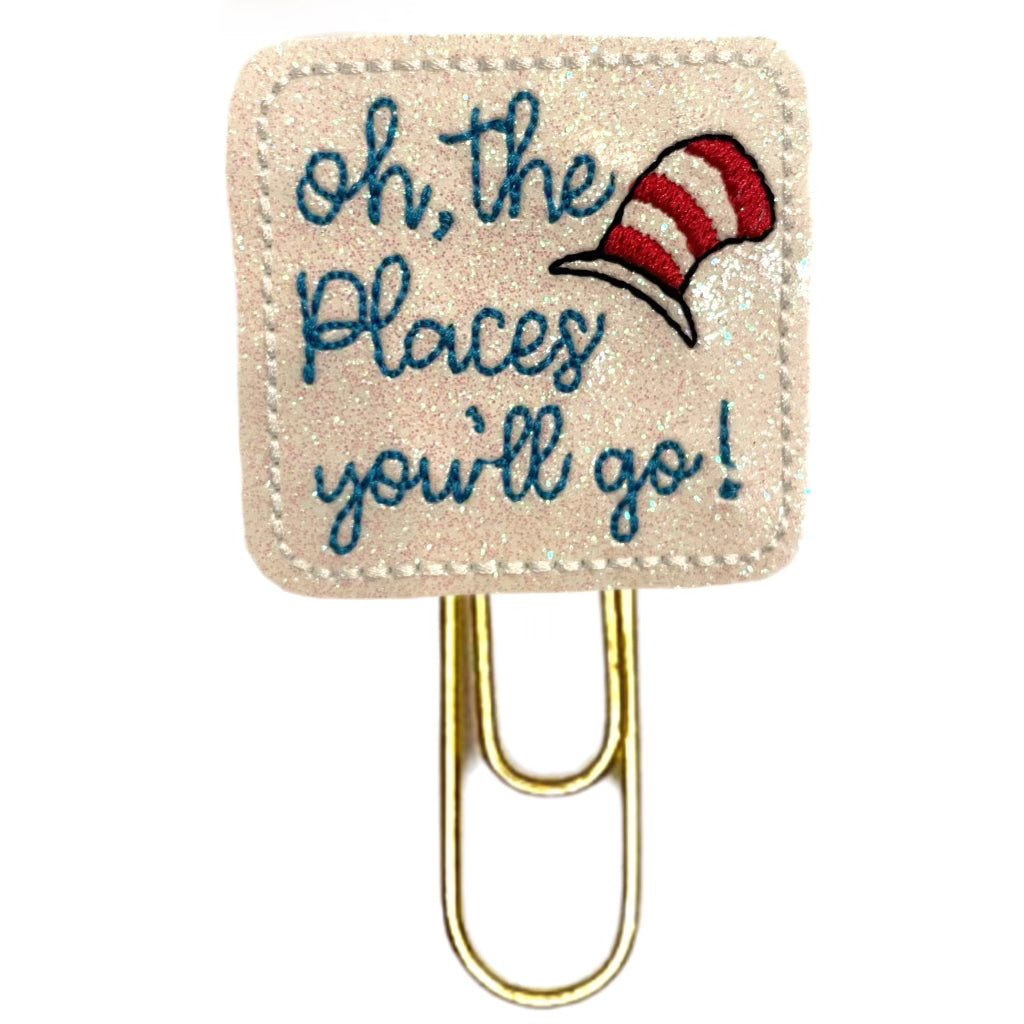 Oh, The Places You'll Go novelty paper clip from Clip Chicks is embroidered onto white shimmery vinyl with the red and white striped silly hat embroidered on it, then attached to a paper clip.